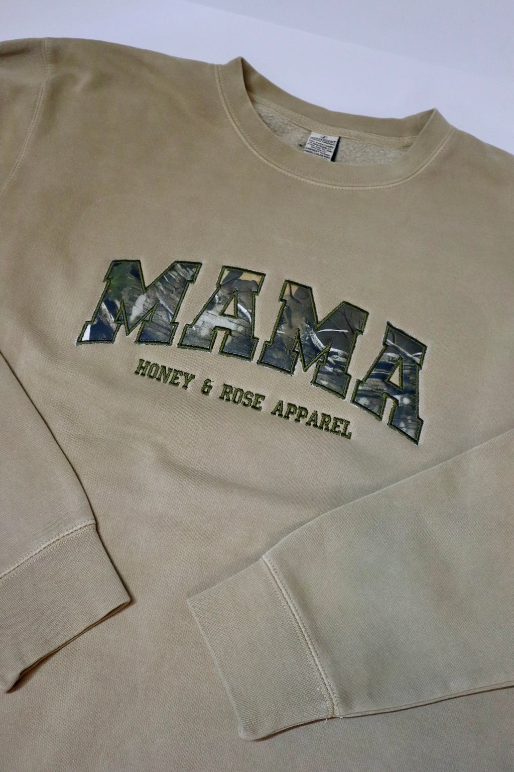 Beige sweatshirt with 'MAMA' and 'Honey & Rose Apparel' text on a white background