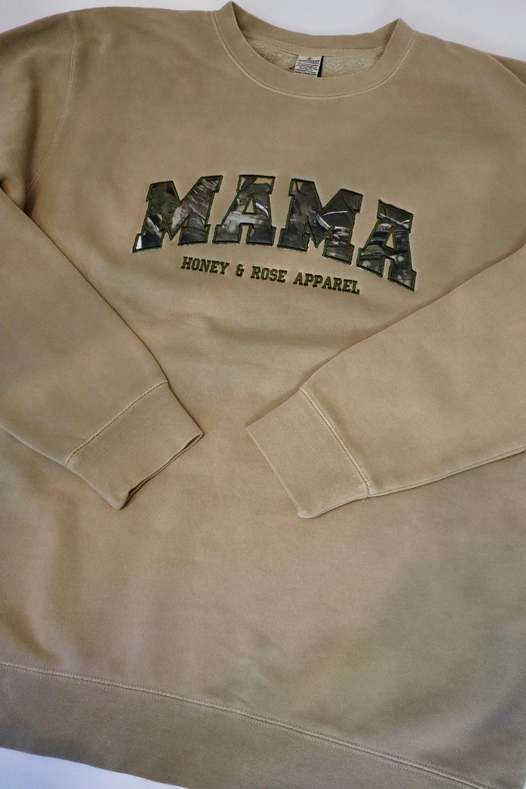 Beige sweatshirt with 'MAMA' printed in camouflage on a white background