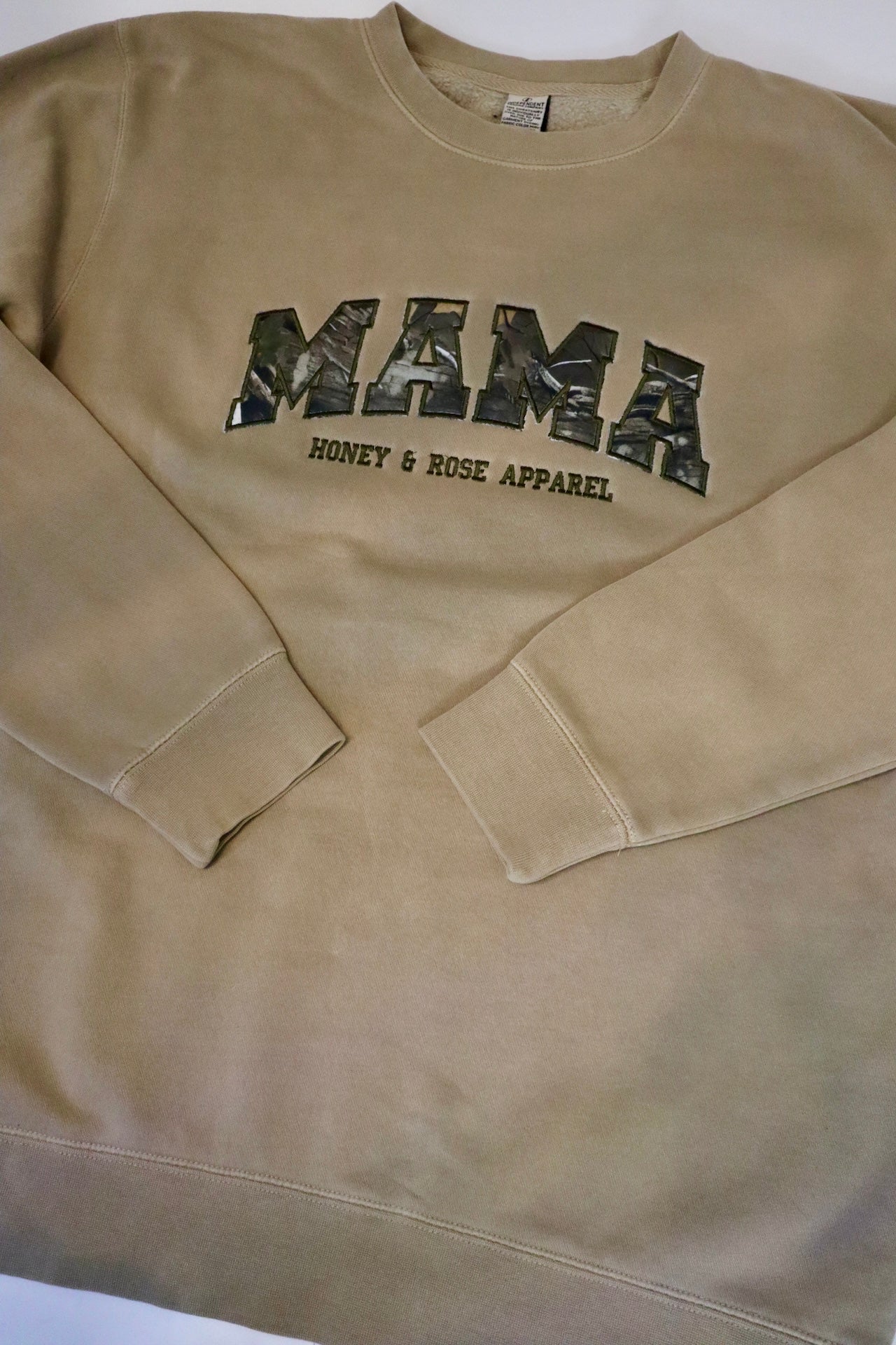 Beige sweatshirt with 'MAMA' printed in camouflage on a white background