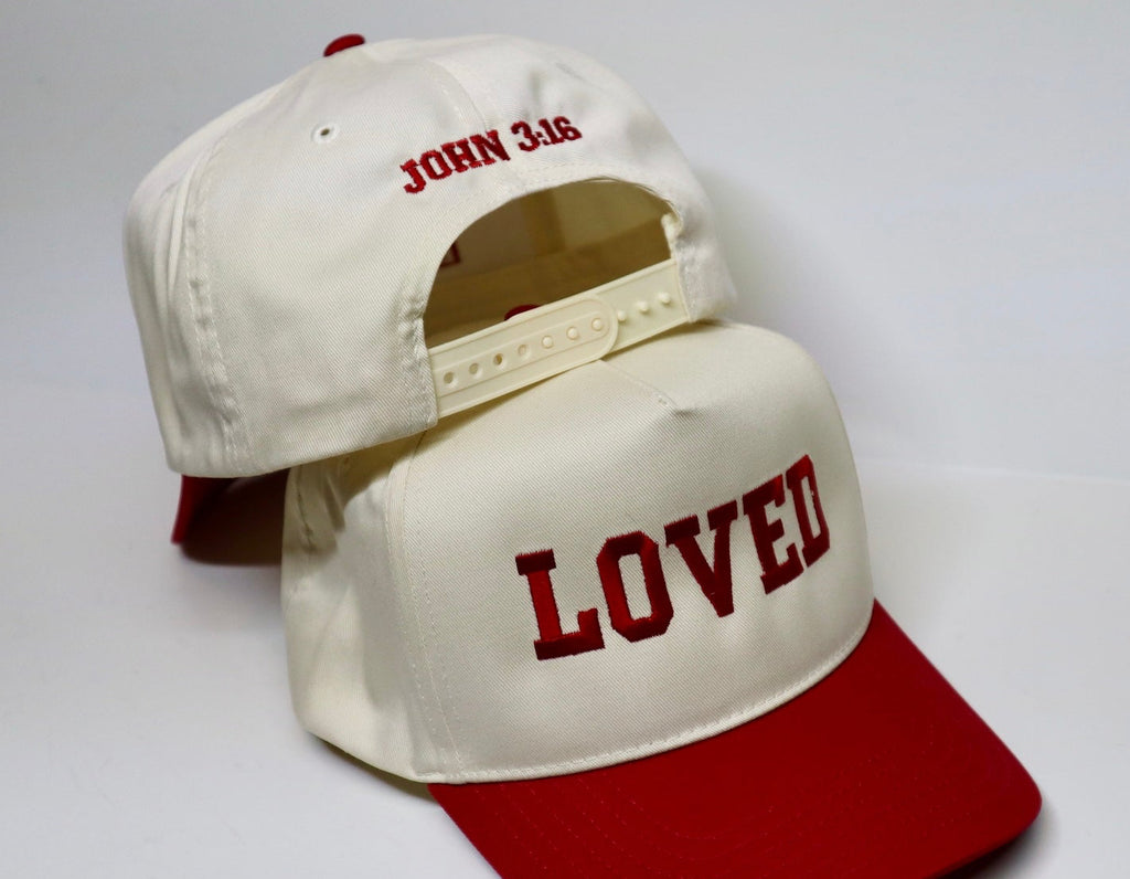 Two baseball caps with 'LOVED' and 'JOHN 3:16' text on a white background