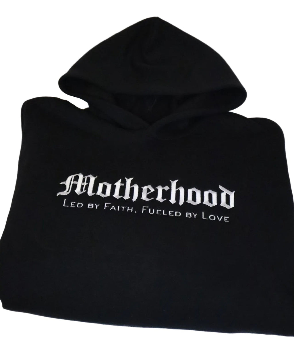 Black hoodie with 'Motherhood Led by Faith, Fueled by Love' text on a white background